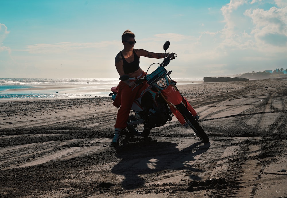 a woman sitting on a dirt bike on the beach