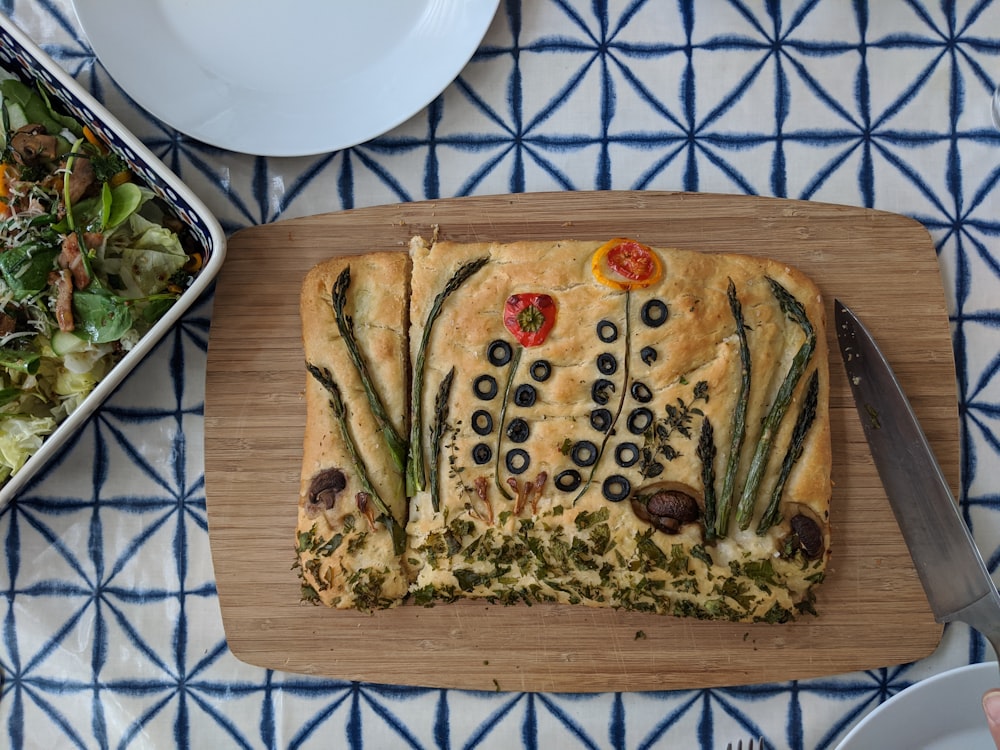 a wooden cutting board topped with a pizza covered in toppings