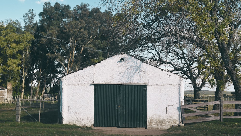 a white building with a green door next to a fence