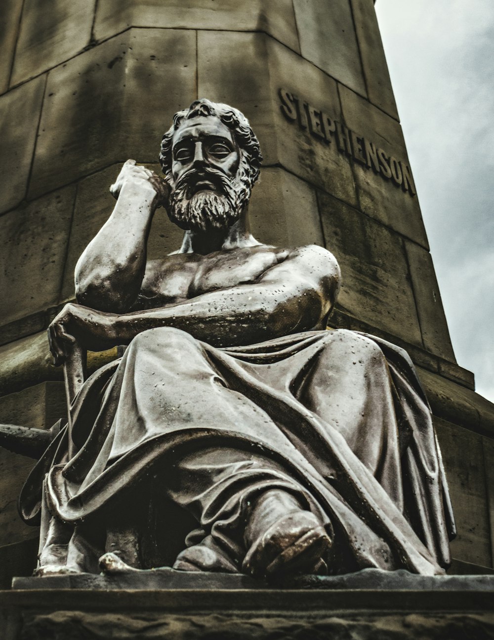 a statue of a man sitting next to a tall tower