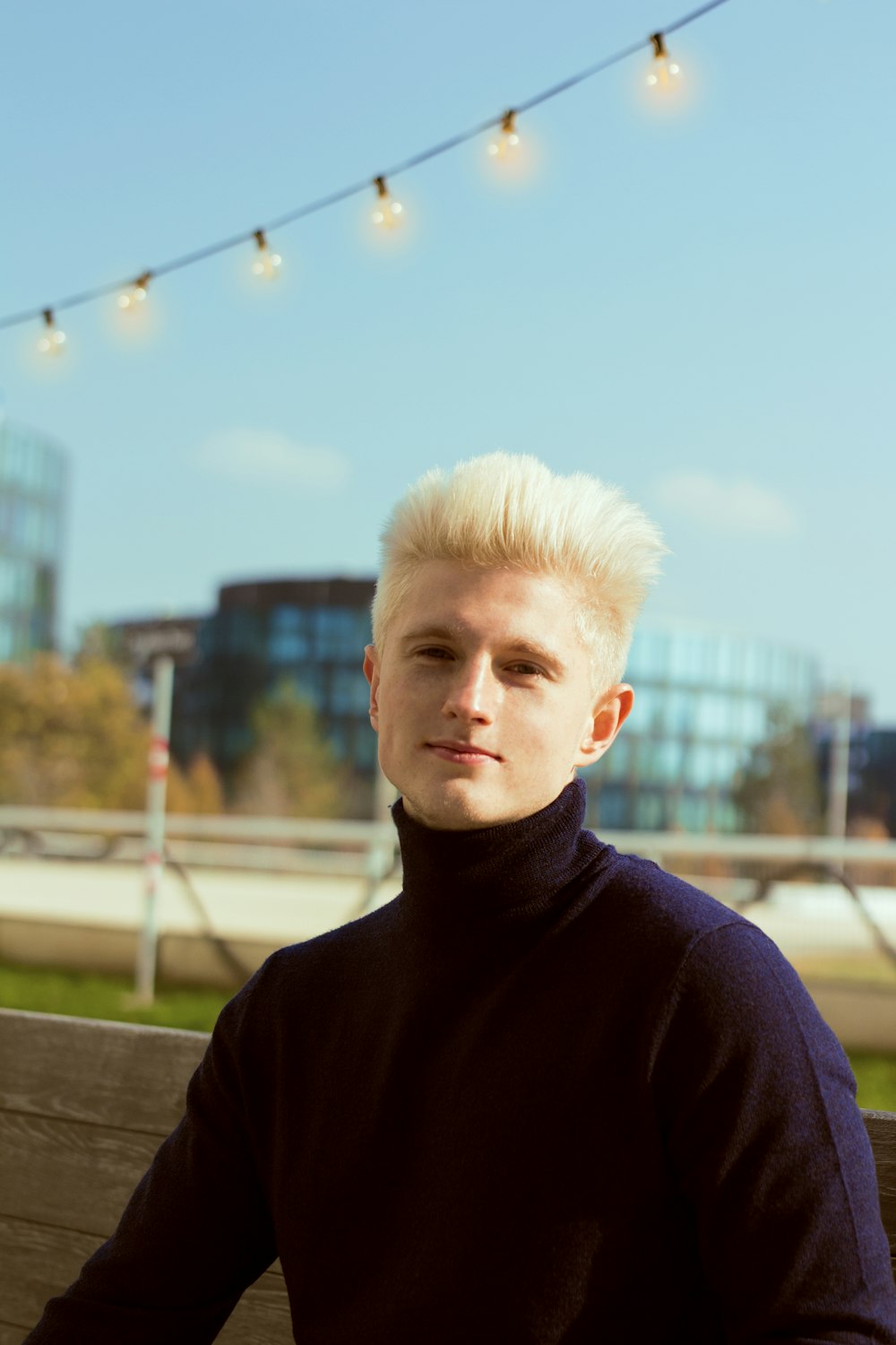 a man with blonde hair sitting on a bench