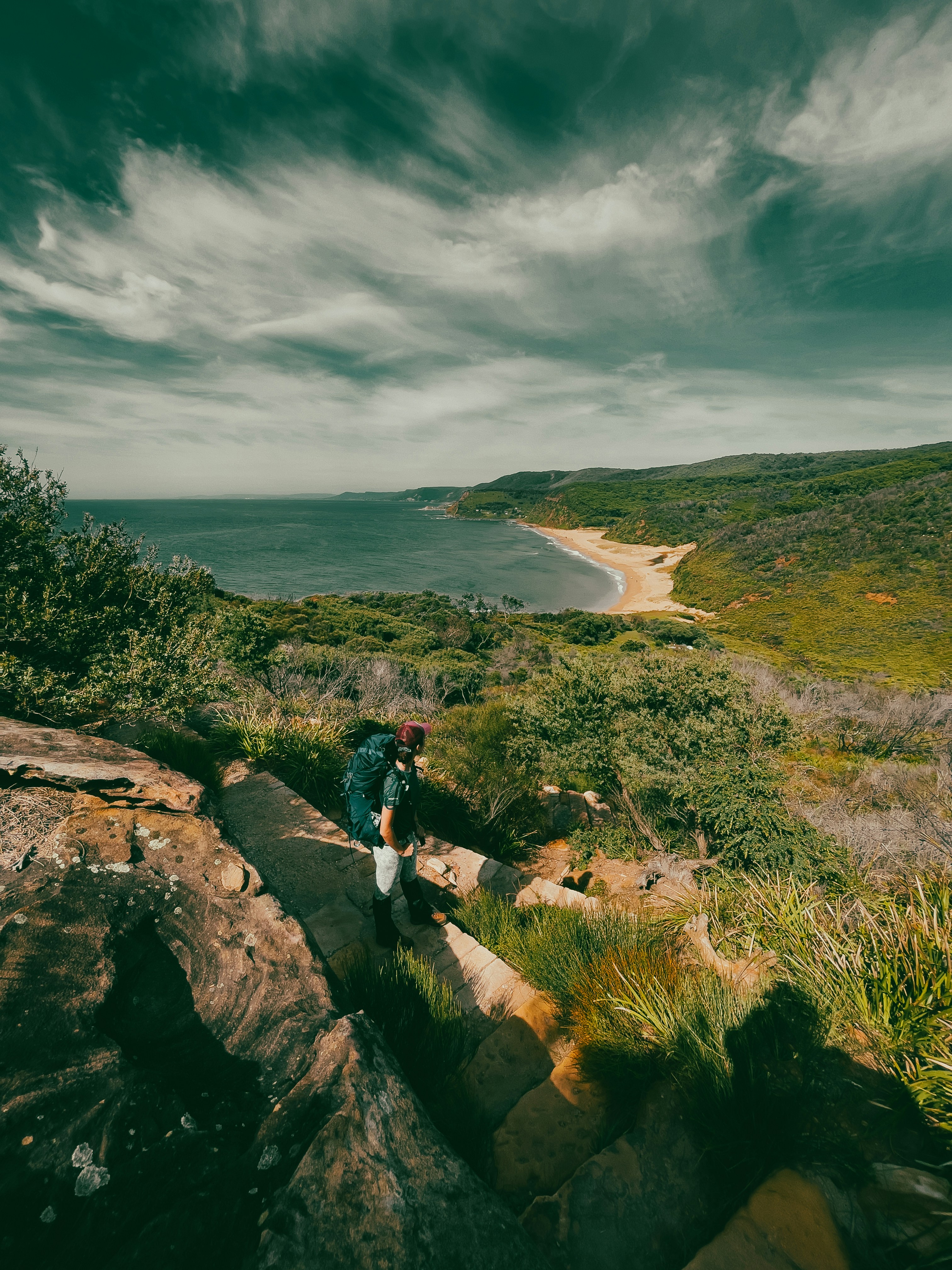 a person walking up a rocky path near the ocean