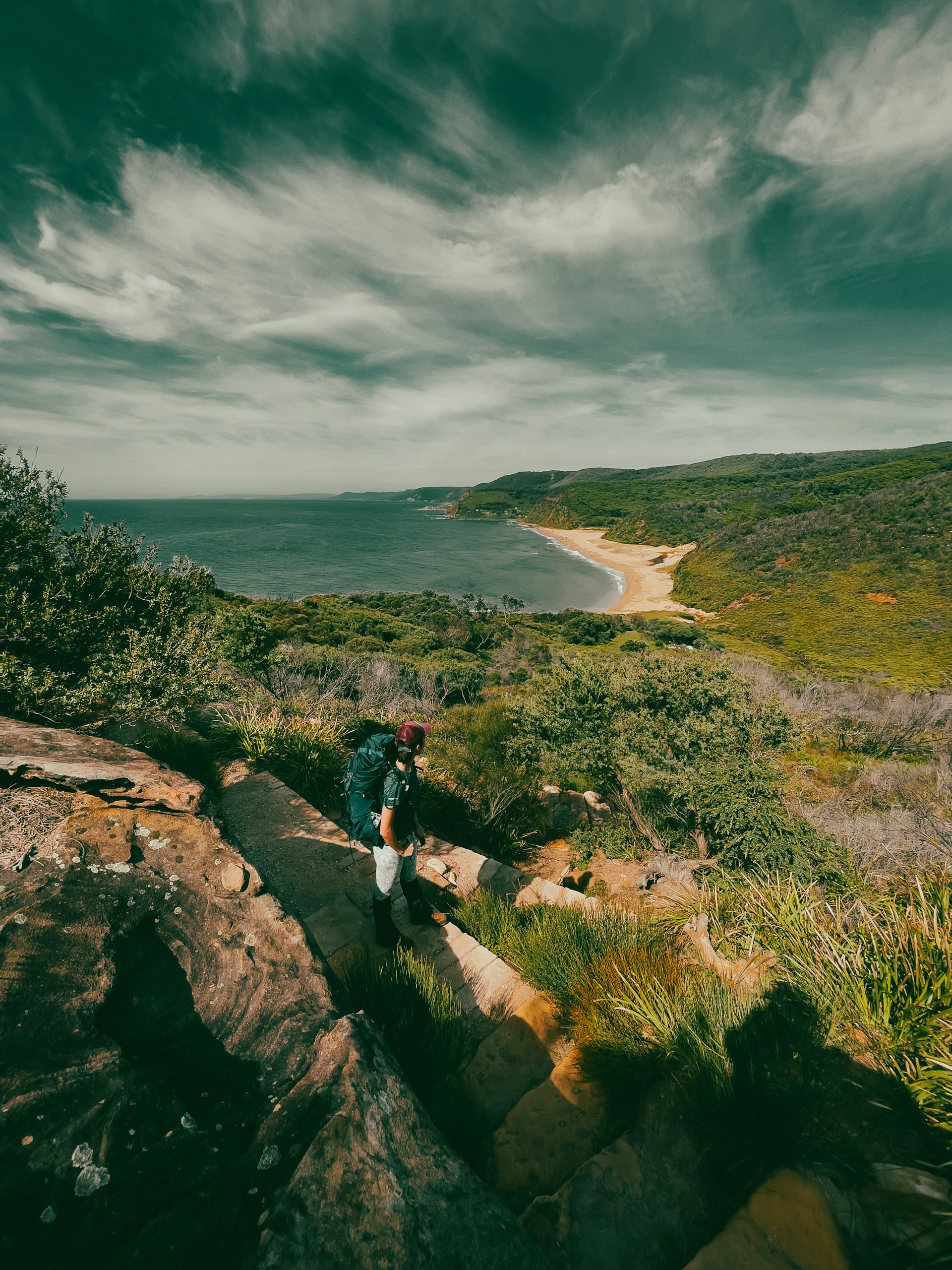 a person walking up a rocky path near the ocean