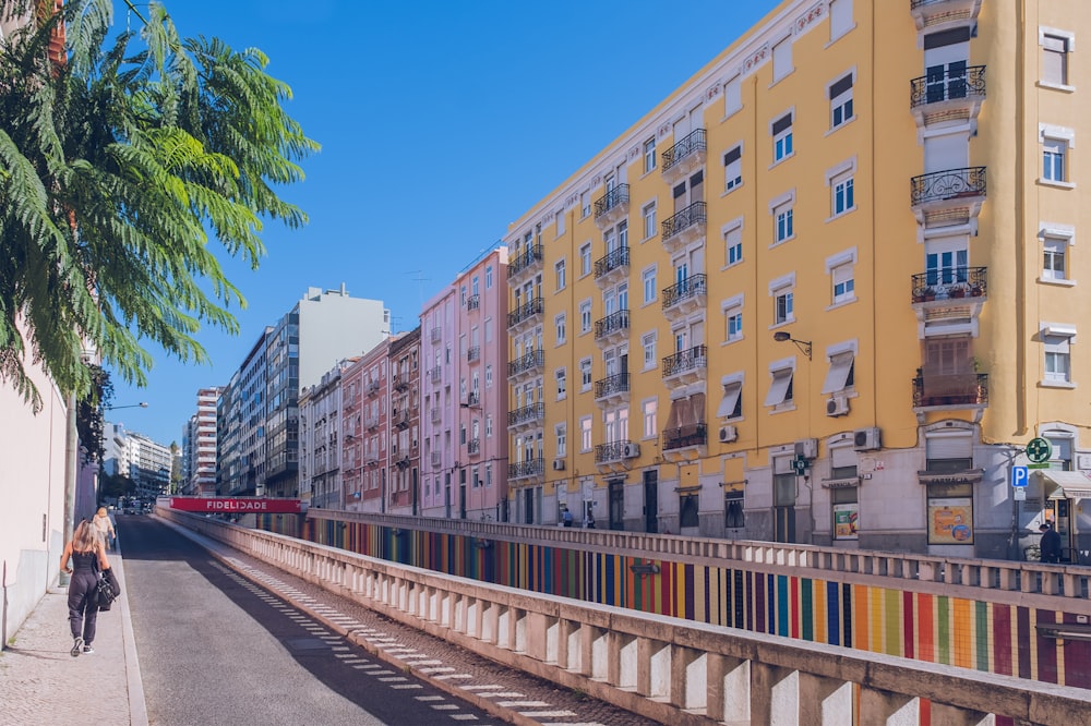 a woman walking down a street next to tall buildings