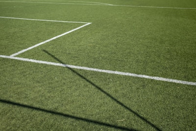 Specialist using a core-aeration unit on a vibrant sports field under bright sunlight.