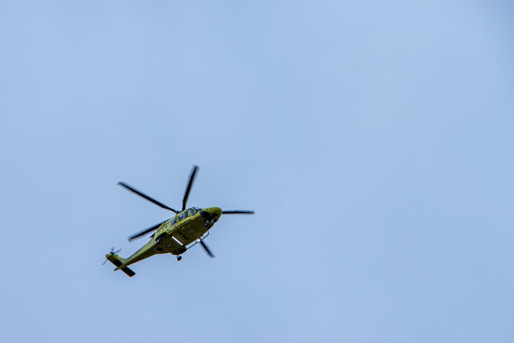 a helicopter flying through a blue sky on a sunny day