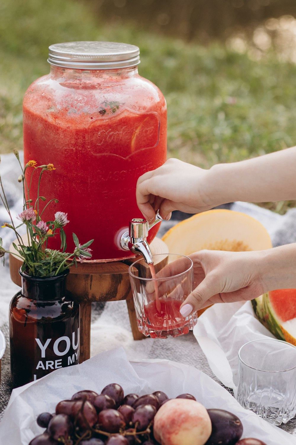 a person holding a glass near a jar of liquid