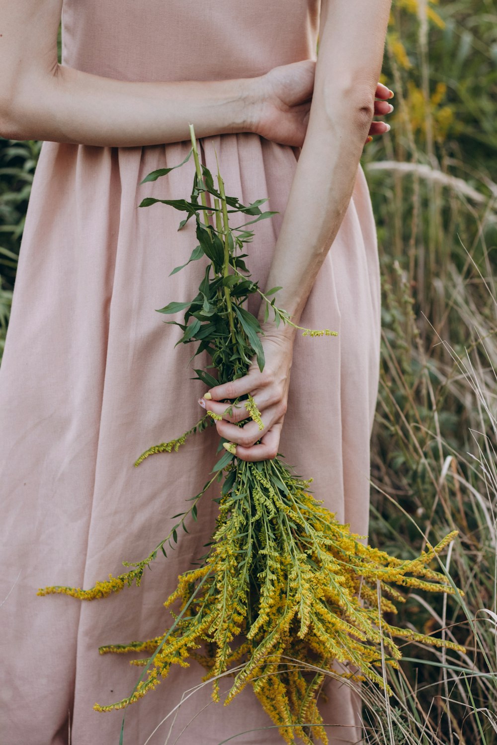 a woman in a pink dress holding a bunch of flowers