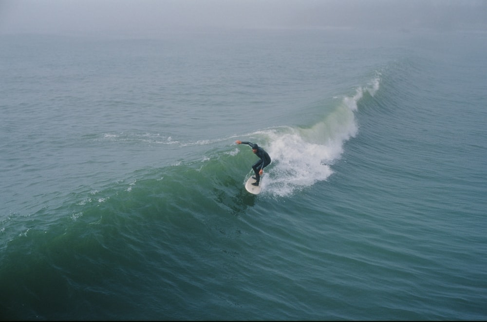 a man riding a wave on top of a surfboard