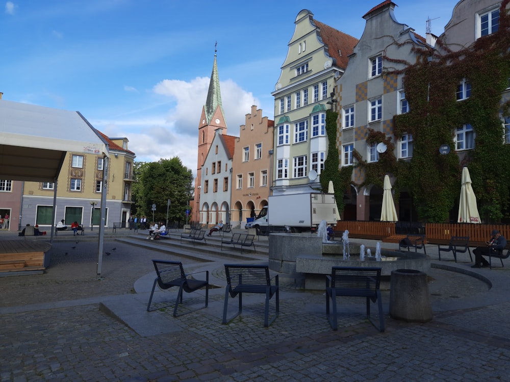 a row of buildings with tables and chairs in the foreground