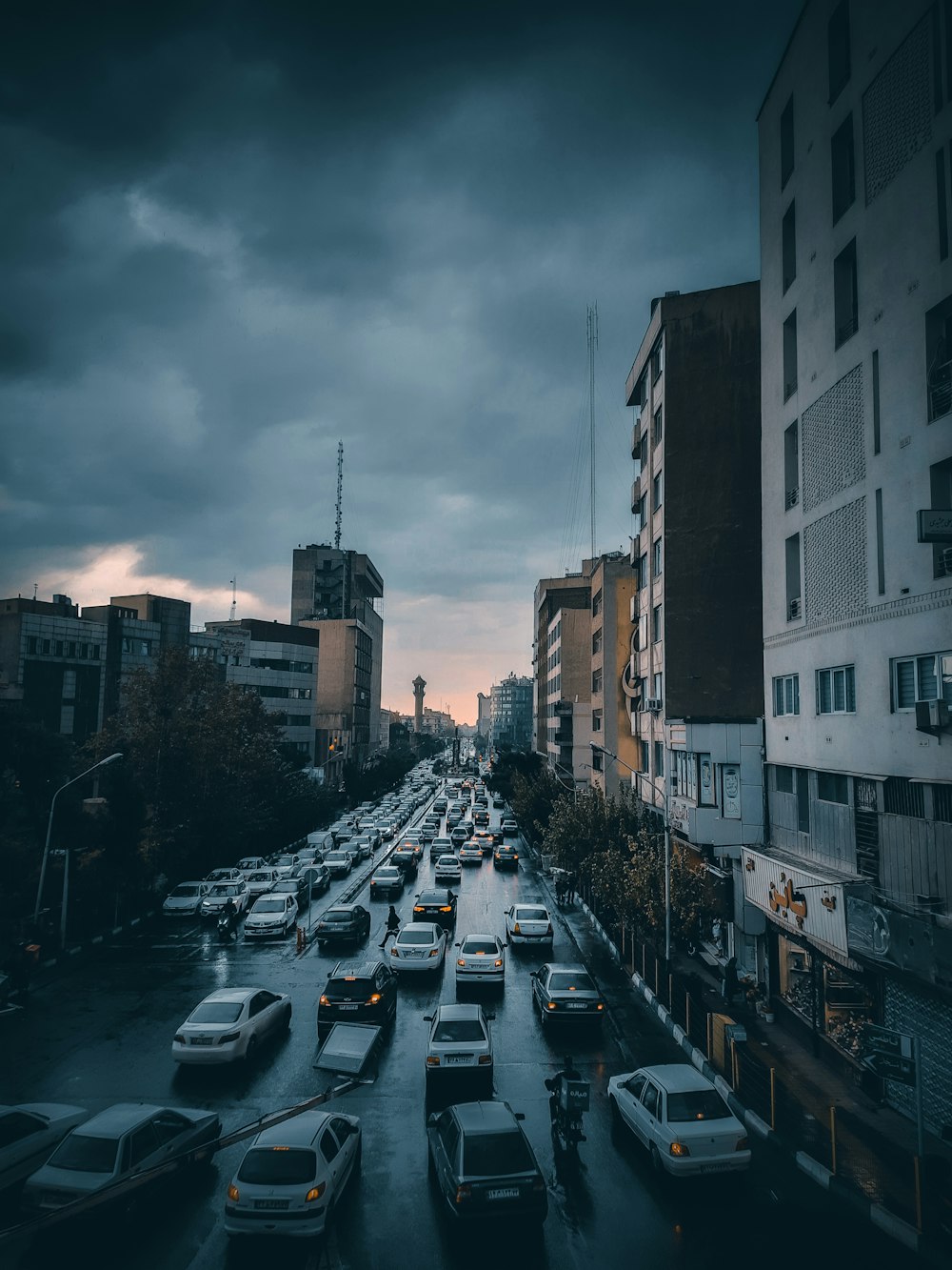 a city street filled with lots of traffic under a cloudy sky