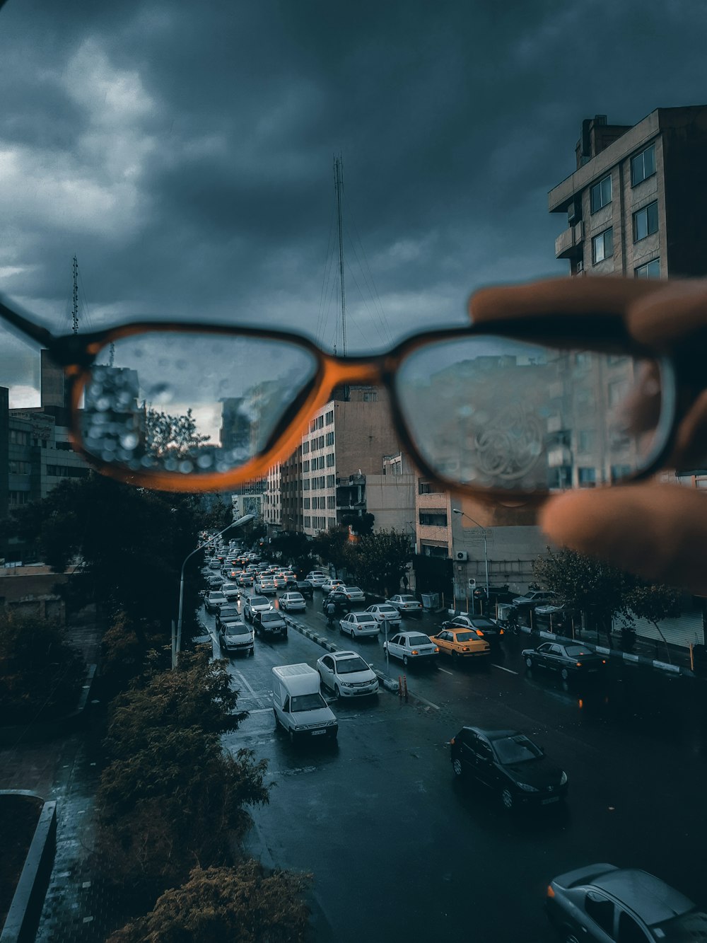 a hand holding a pair of glasses over a city street