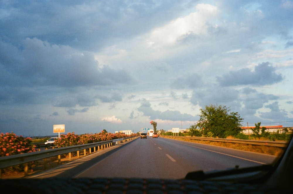 a car driving down a road under a cloudy sky