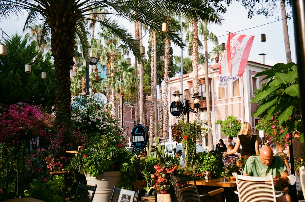 a woman sitting at a table in a garden filled with potted plants