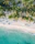 an aerial view of a beach with chairs and palm trees