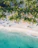 an aerial view of a beach with chairs and palm trees