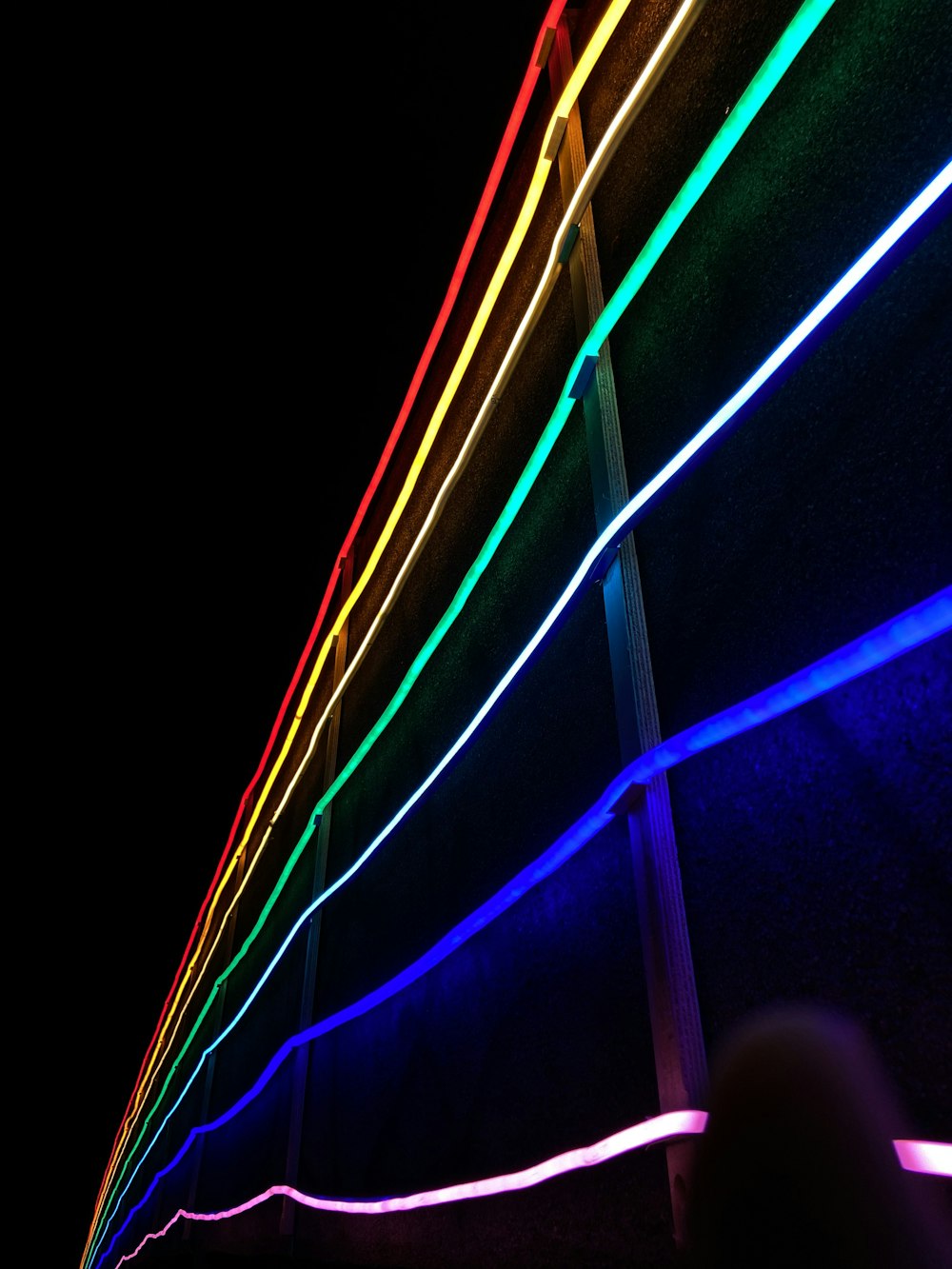 a person standing in front of a neon wall