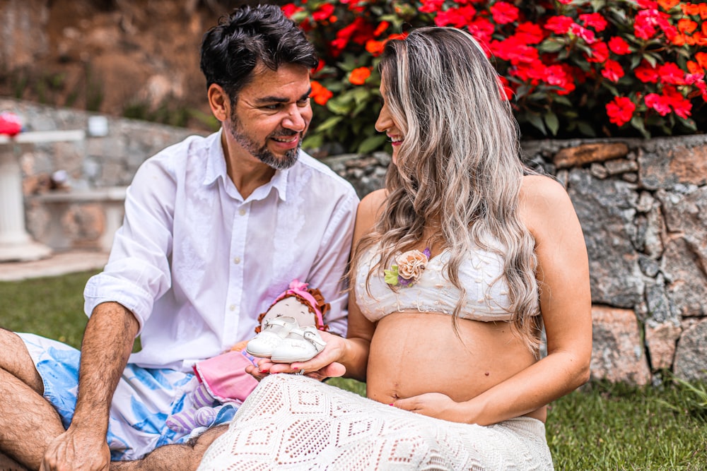 um homem e uma mulher grávida sentados na grama