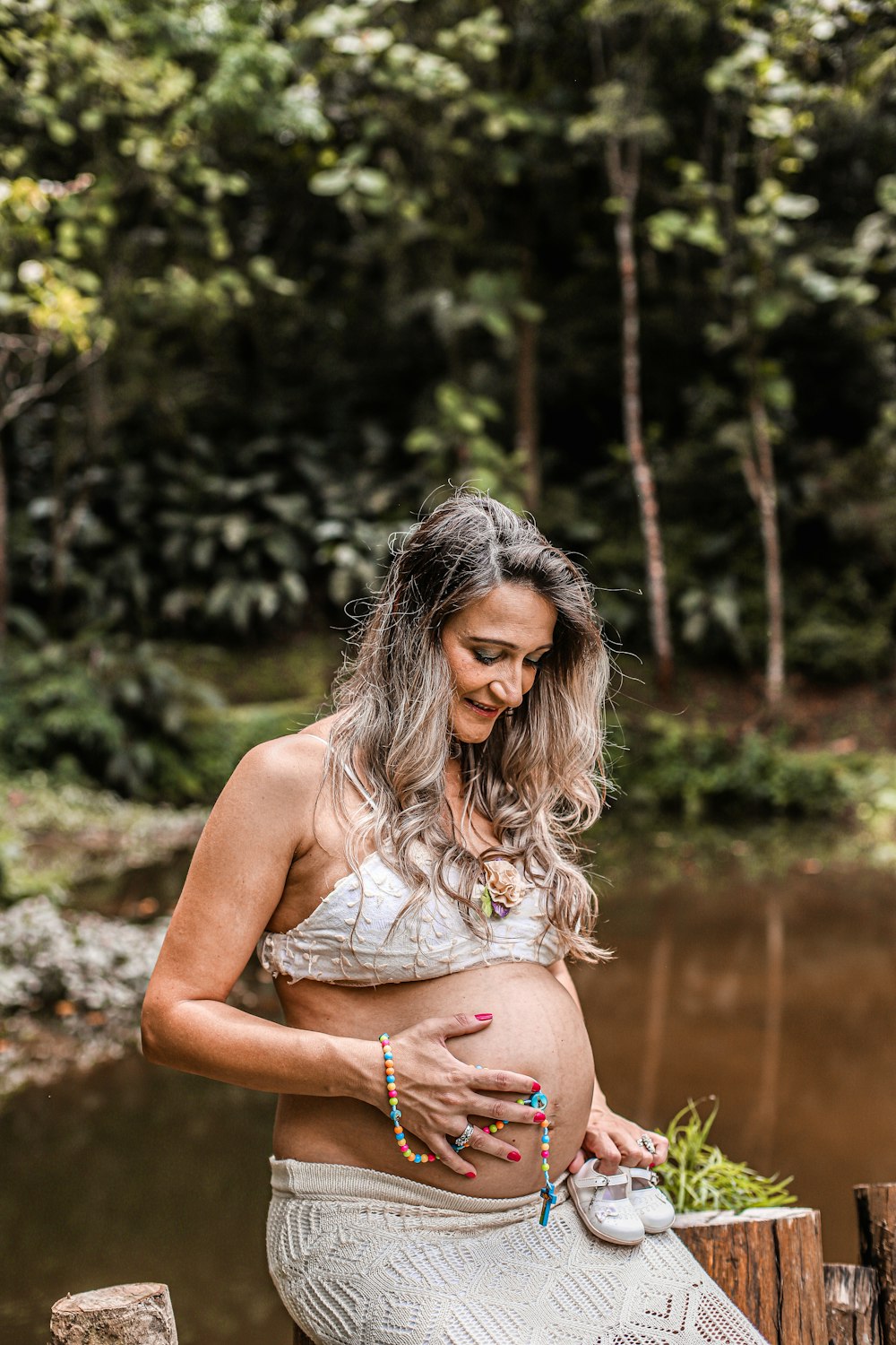 a pregnant woman sitting on a log in a forest