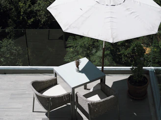 A compact outdoor bistro set with stackable patio chairs on a sunny balcony.