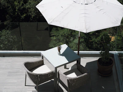 A compact outdoor bistro set with stackable patio chairs on a sunny balcony.