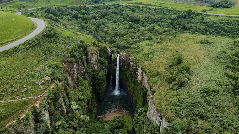 a large waterfall in the middle of a lush green valley