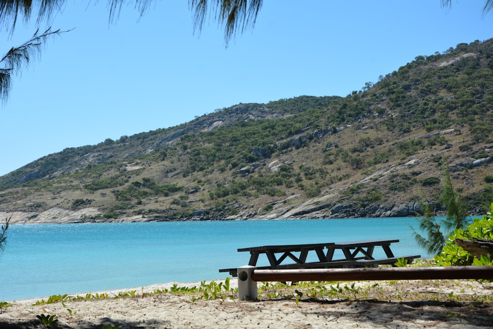 a wooden bench sitting on top of a sandy beach