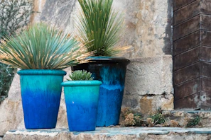 a couple of blue pots sitting on top of a stone wall