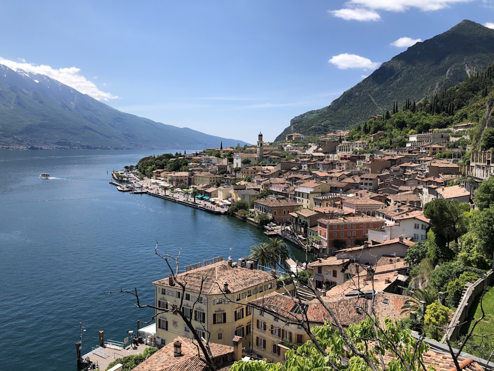 a village on the shore of a lake with mountains in the background