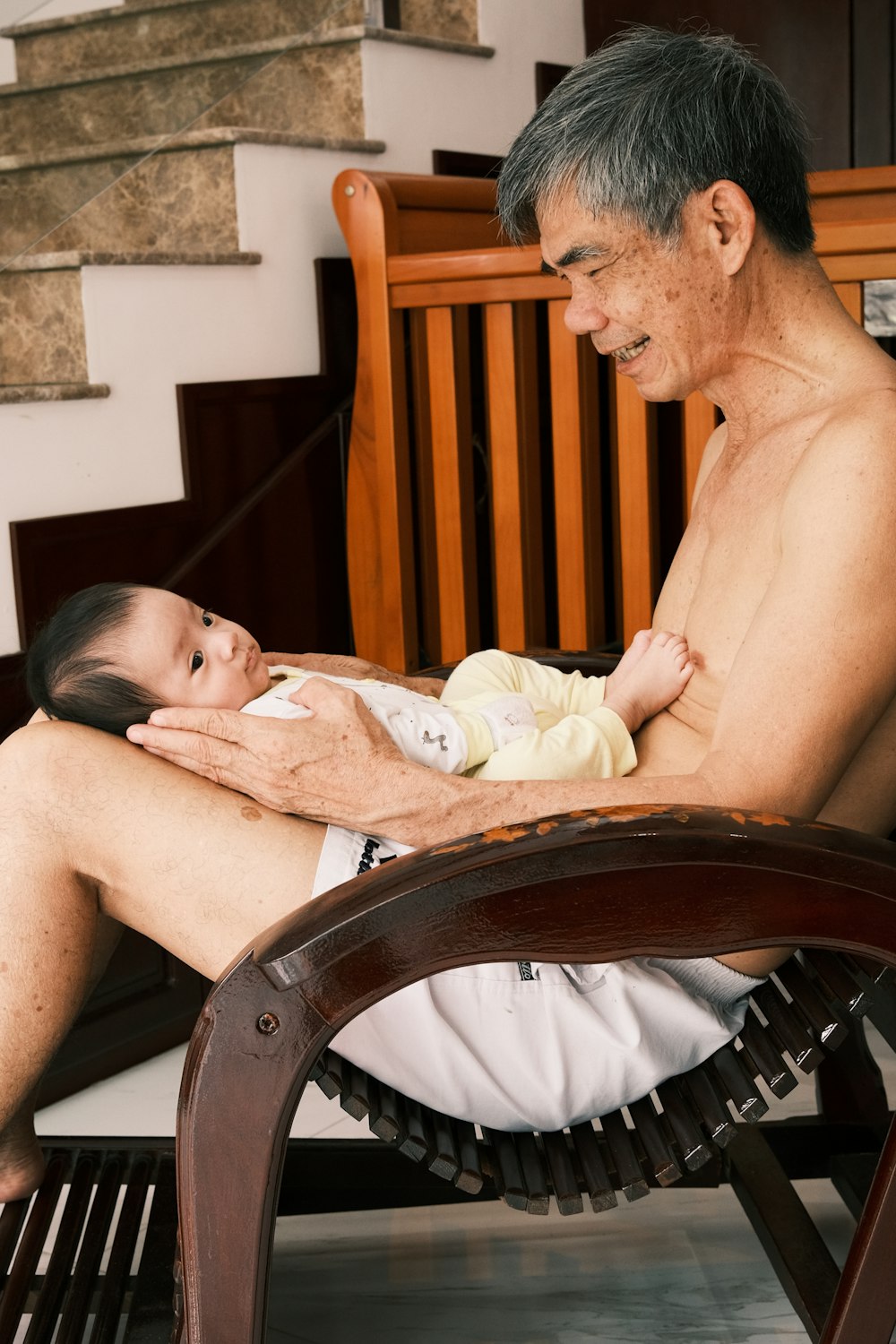 un homme assis sur une chaise tenant un bébé