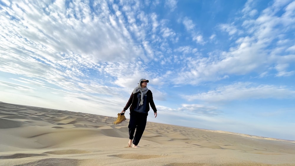 Un hombre caminando por una playa de arena bajo un cielo azul