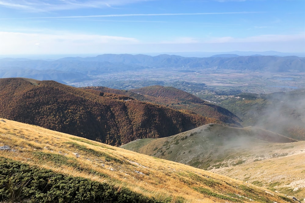 a view of a valley and mountains from a hill