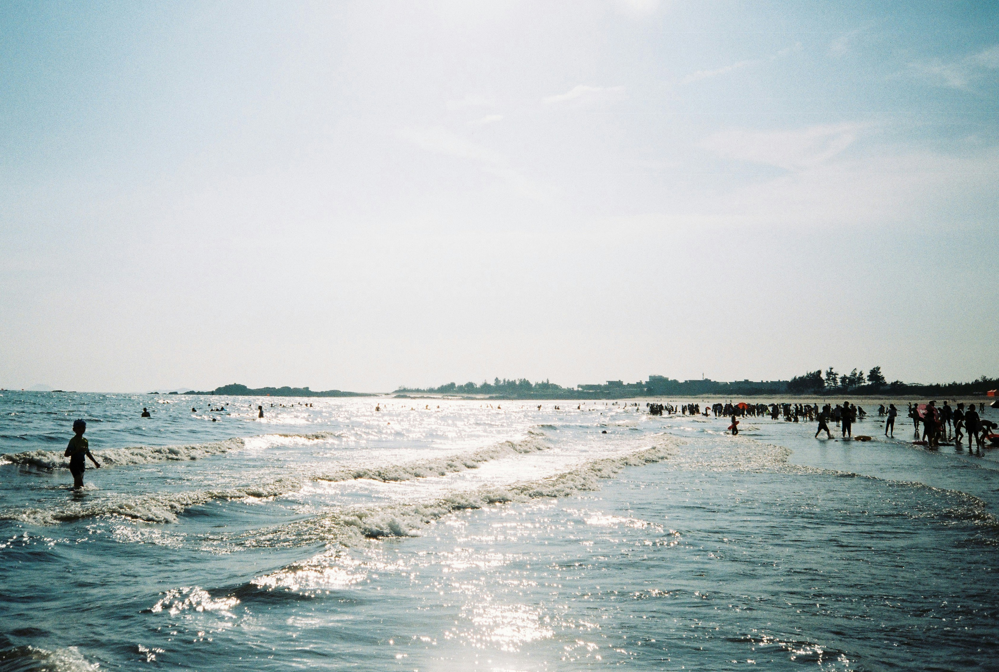 a group of people standing on top of a beach next to the ocean