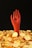 A stylized red hand emerges from a pile of shiny golden coins, each marked with the Bitcoin symbol, against a dark background.