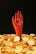 A stylized red hand emerges from a pile of shiny golden coins, each marked with the Bitcoin symbol, against a dark background.