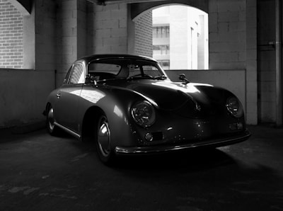 Sleek, polished classic car parked in a sunlit garage with reflections on its hood.