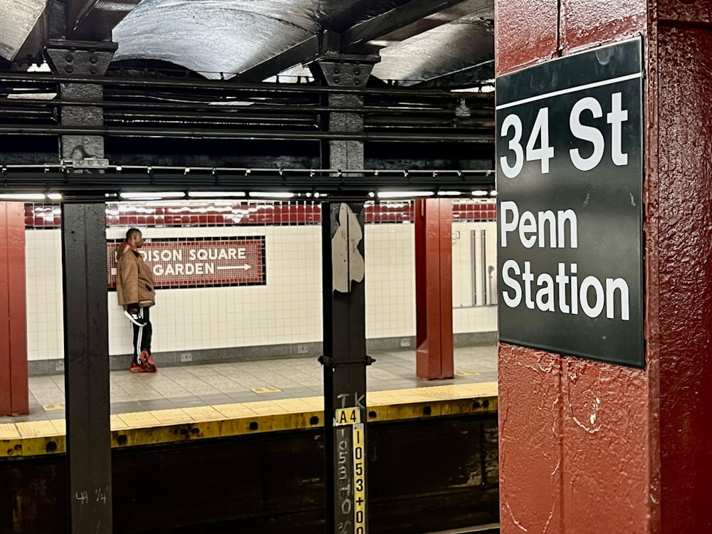 a person standing on a train platform next to a sign