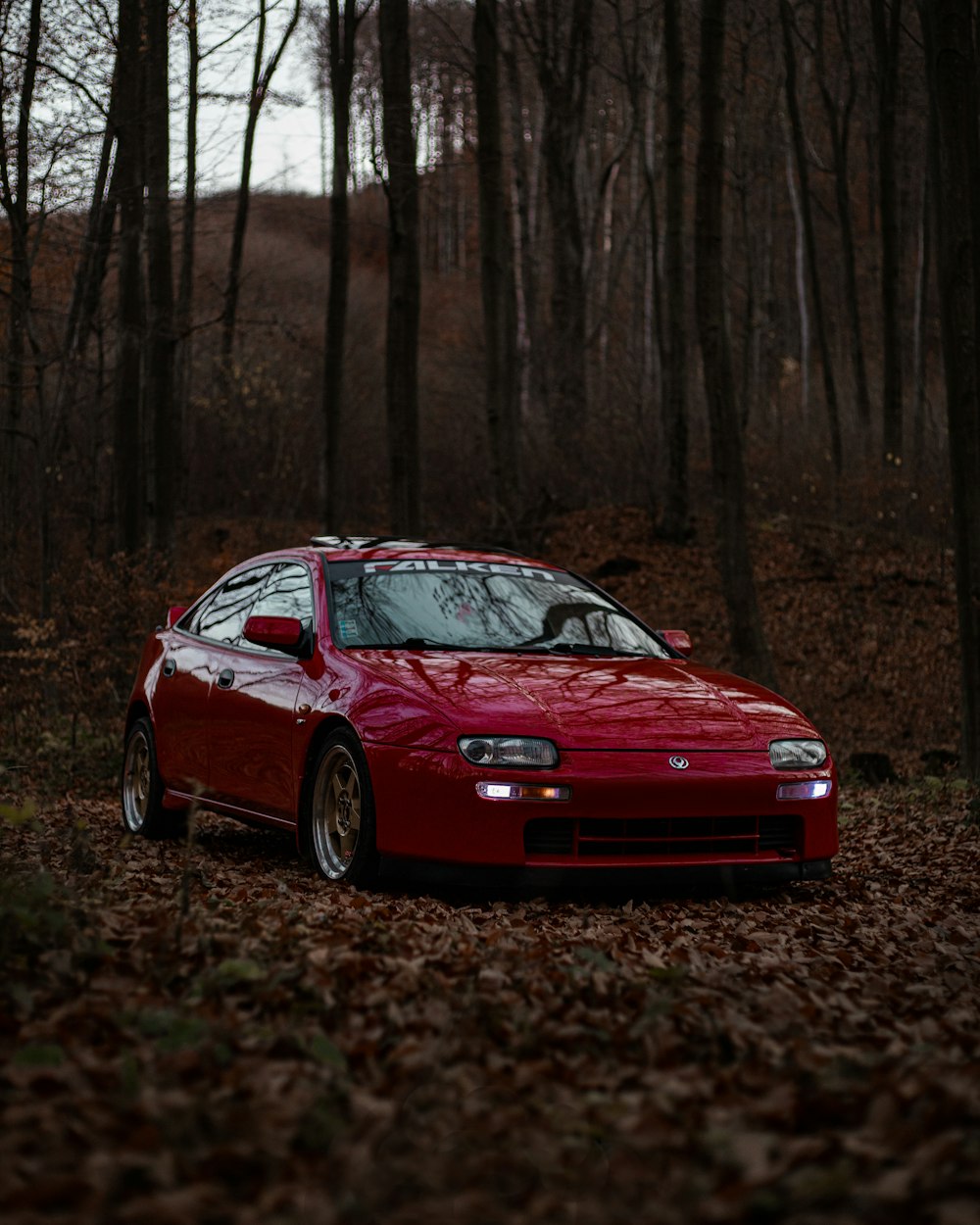 a red sports car parked in a wooded area