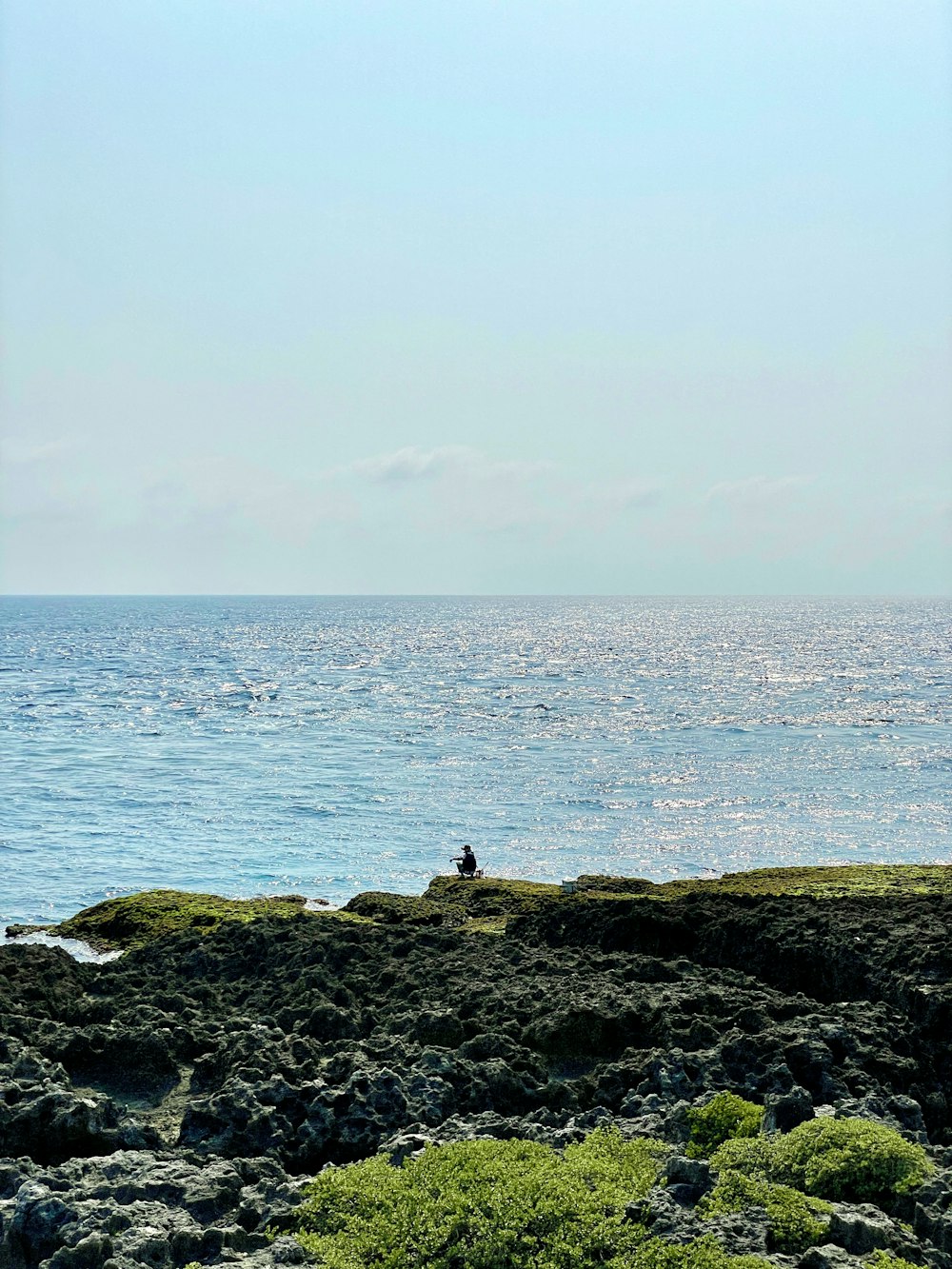 a person sitting on a rock near the ocean