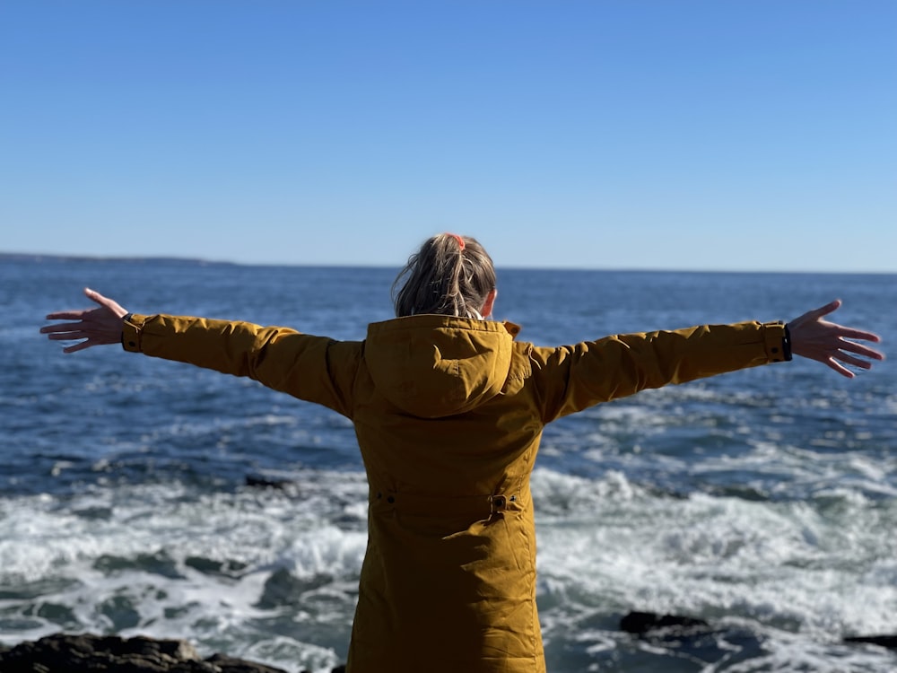 a woman standing on a beach with her arms outstretched