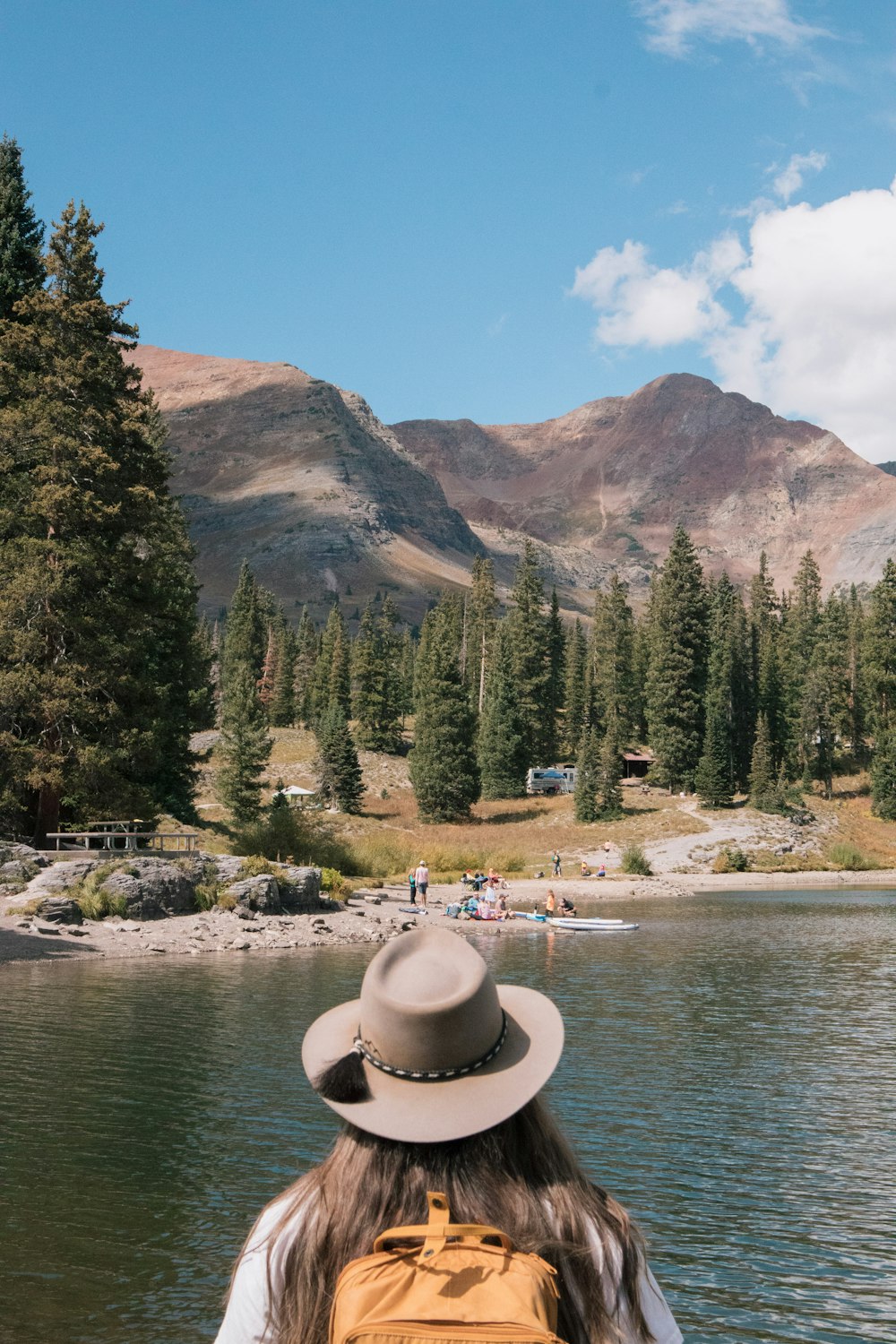 a woman with a hat is looking out over a lake