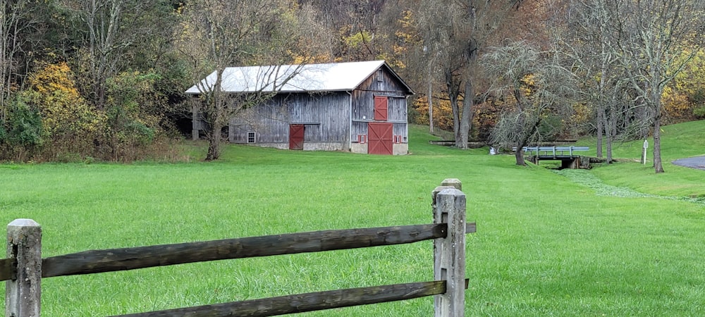 a barn sits in the middle of a grassy field