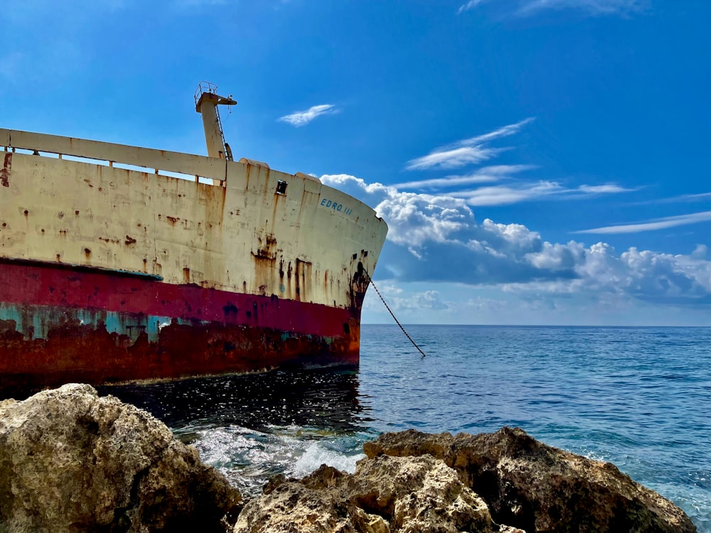 um barco enferrujado sentado no topo de uma praia rochosa