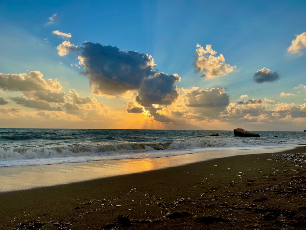 the sun is setting over the ocean on the beach