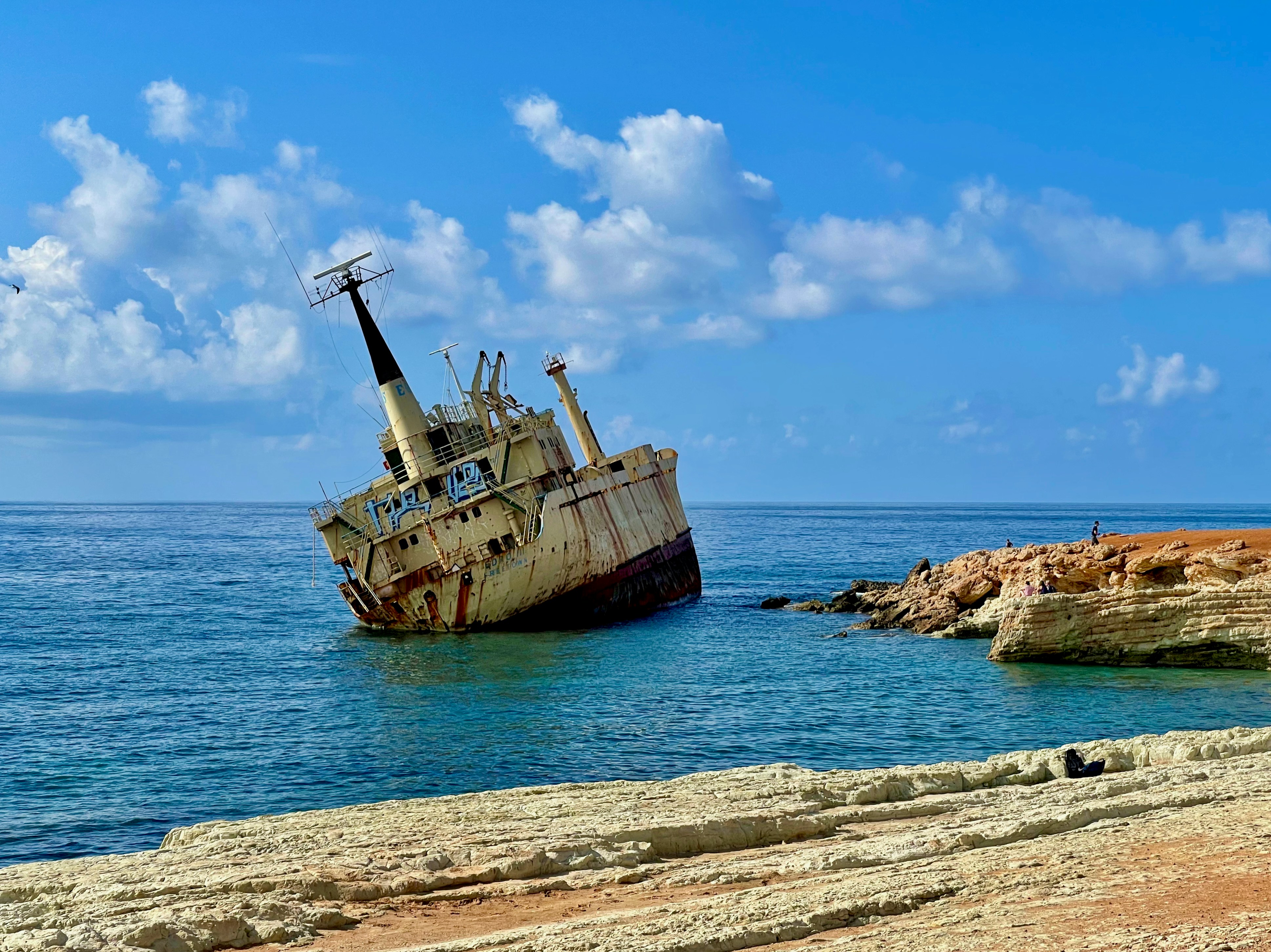 an old boat sitting in the middle of the ocean