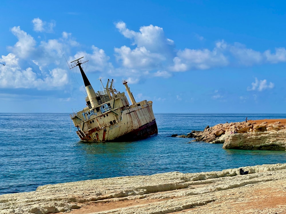 an old boat sitting in the middle of the ocean