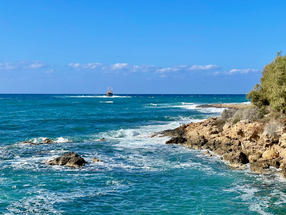 Un bateau est dans l’eau près d’un rivage rocheux