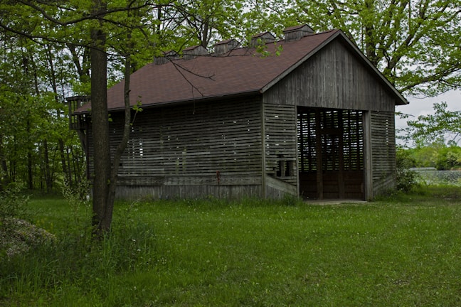 an old wooden building sitting in the middle of a field
