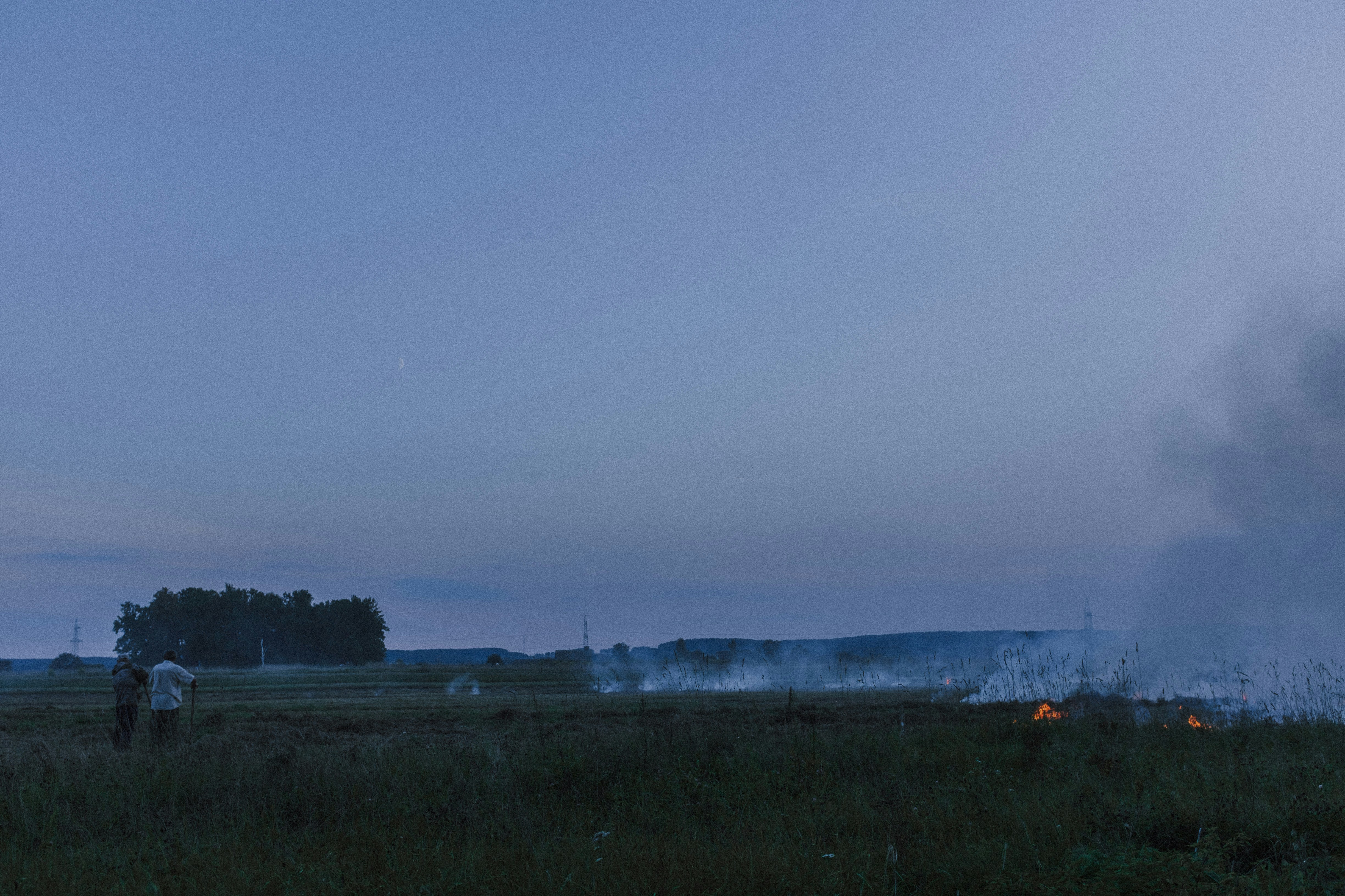 a man standing in a field next to a fire