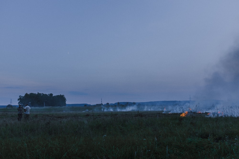 a man standing in a field next to a fire